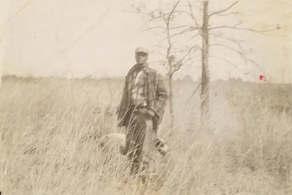 Scalloped-edge family print — a hunter standing in the broomsedge with his dog